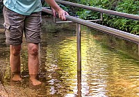 Person in kurzer Hose beim barfuß Wassertreten im Kneipp-Becken