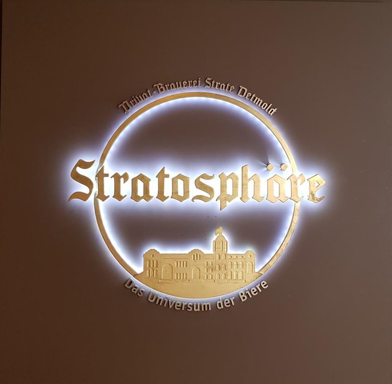 Emblem für die Stratosphäre: Ein dünner Kreis, unten das Bild der Brauerei, in der Mitte der Schriftzug „Stratosphäre“