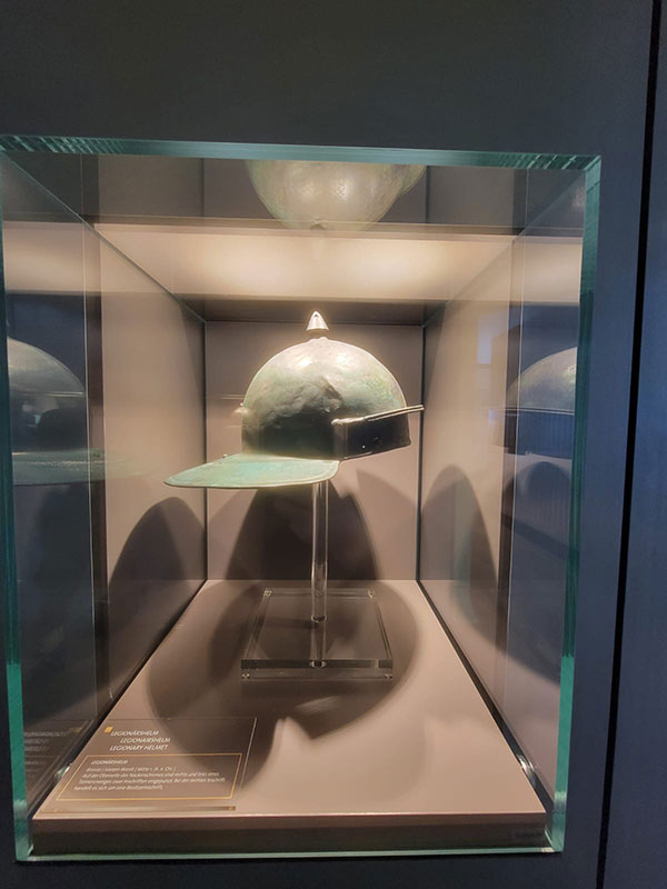 Helm als Ausstellungsstück in einer beleuchteten Glasvitrine